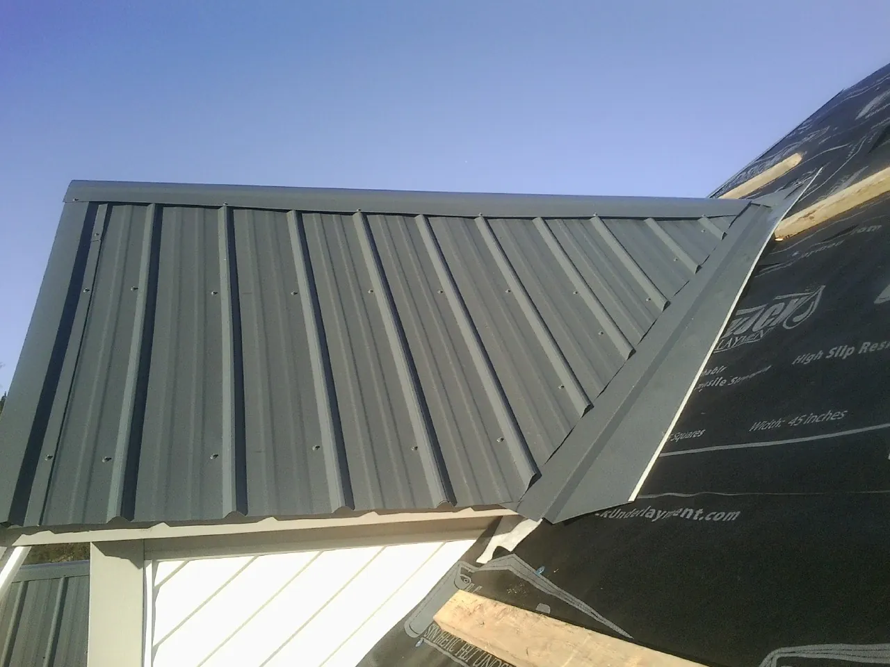 Gray metal roof panels going on over a garage gable in Noatak