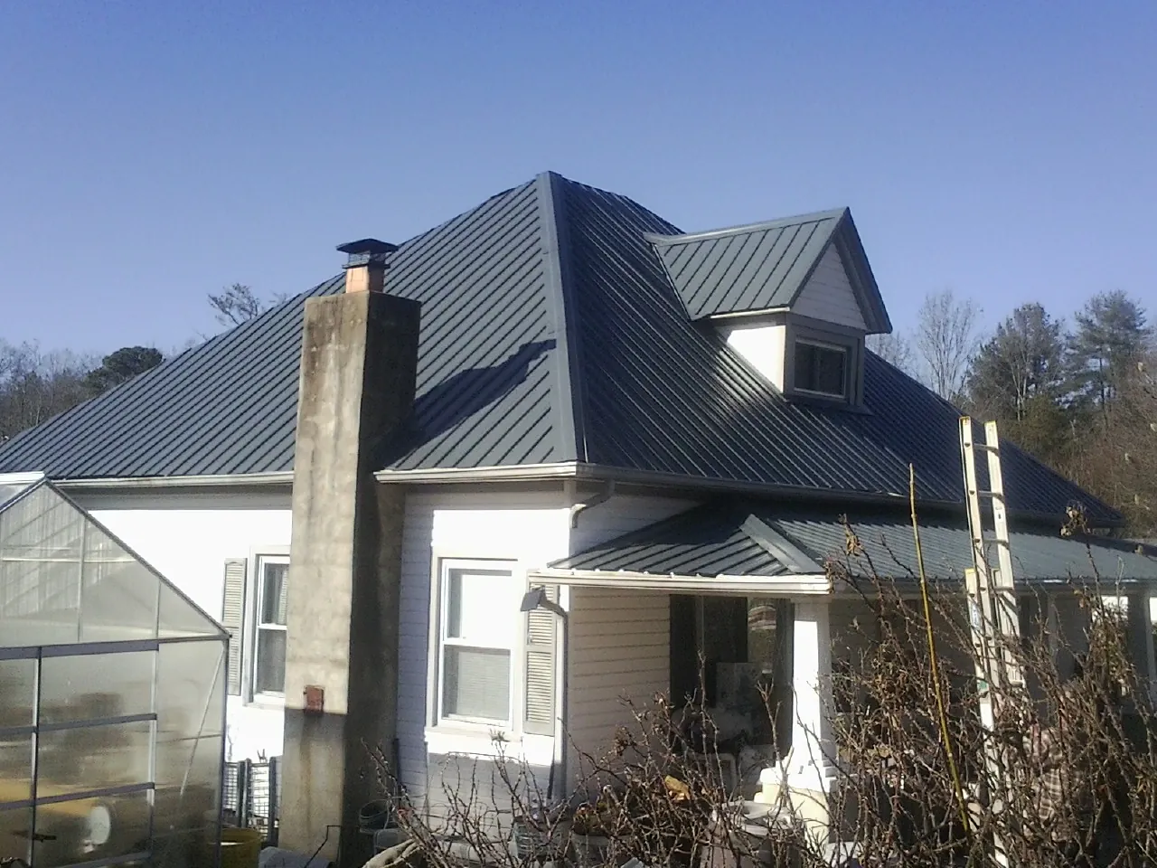Dark blue standing seam metal roof on a white farmhouse with dormer — Slate & Tile Roof Repair by Roofing Brothers in Noatak