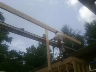 Carpenter setting a ridge beam over a new addition frame — Ice Dam Removal by Roofing Brothers in Noatak