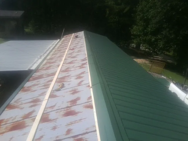 Old rusted panels beside newly installed green metal roofing — Wind Damage Roof Repair by Roofing Brothers in Noatak