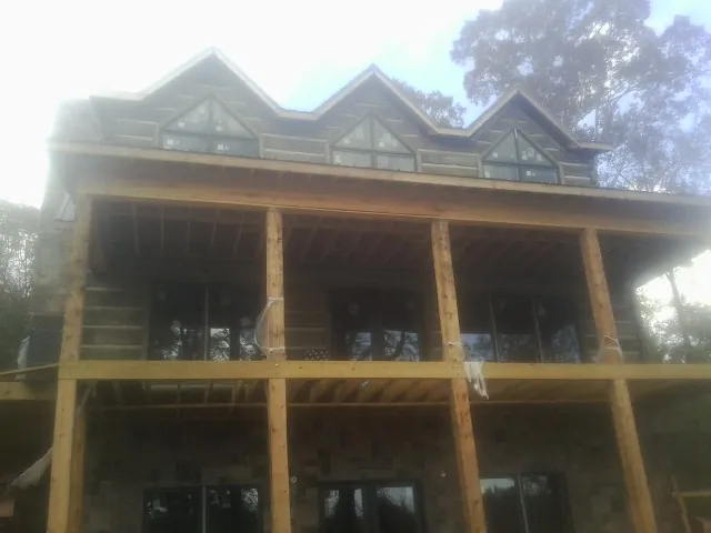 Dormers and porch framing on a large log home under construction — Roof Coating work by our crew in Noatak