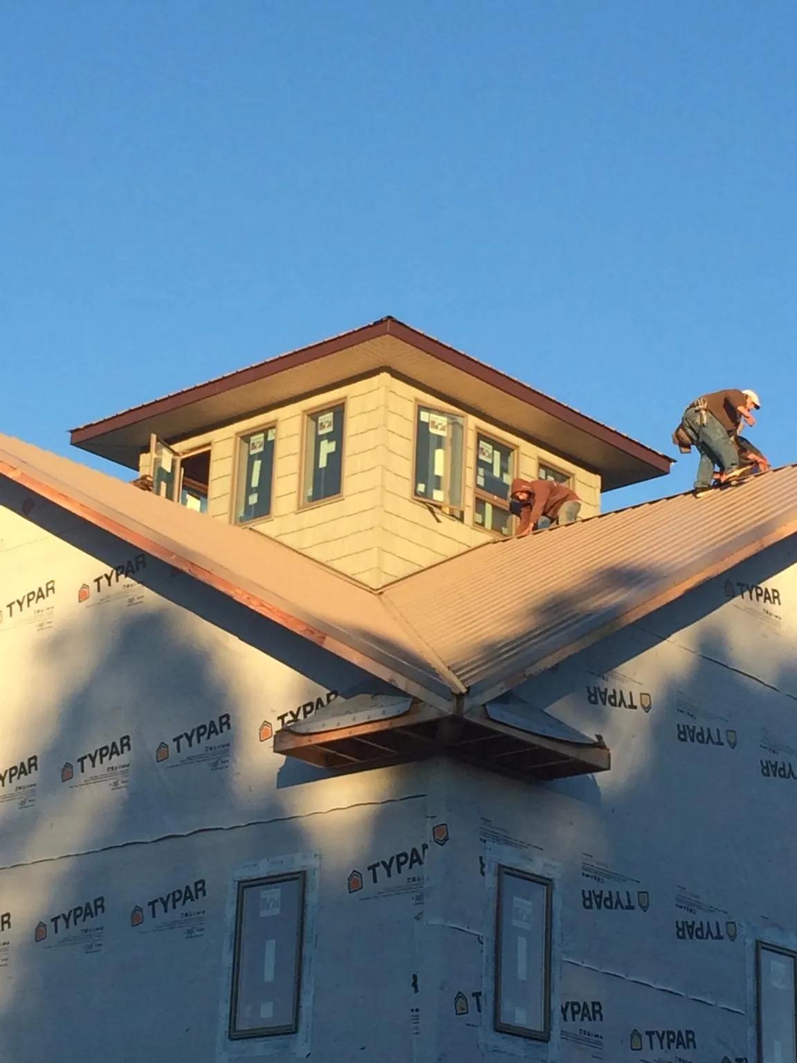 Roofers working around a rooftop cupola on a new metal roof at sunset — Roof Waterproofing in Noatak by Roofing Brothers